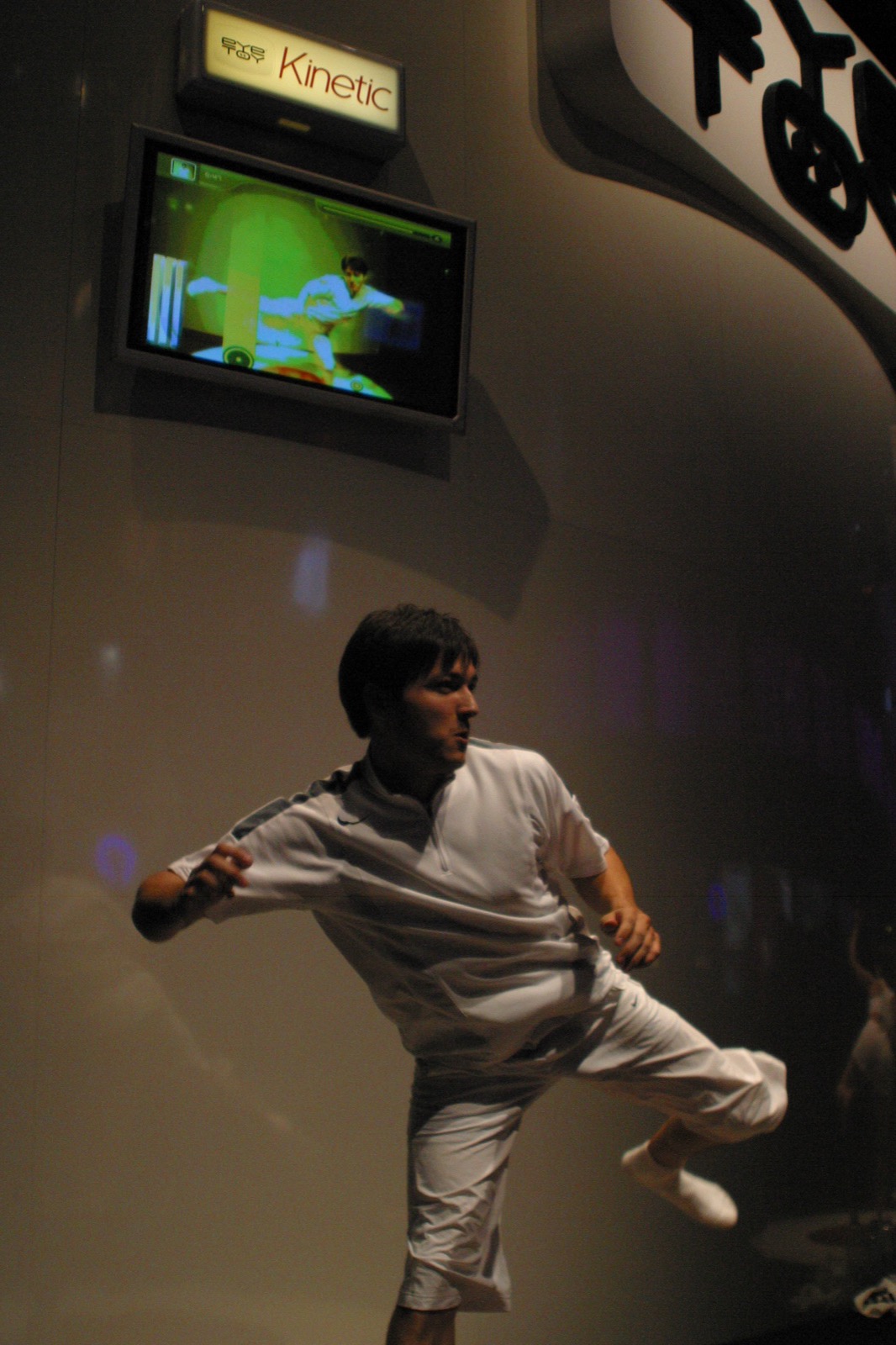A performer demonstrating EyeToy: Kinetic with acrobatic breakdancing moves, mirrored on screen.