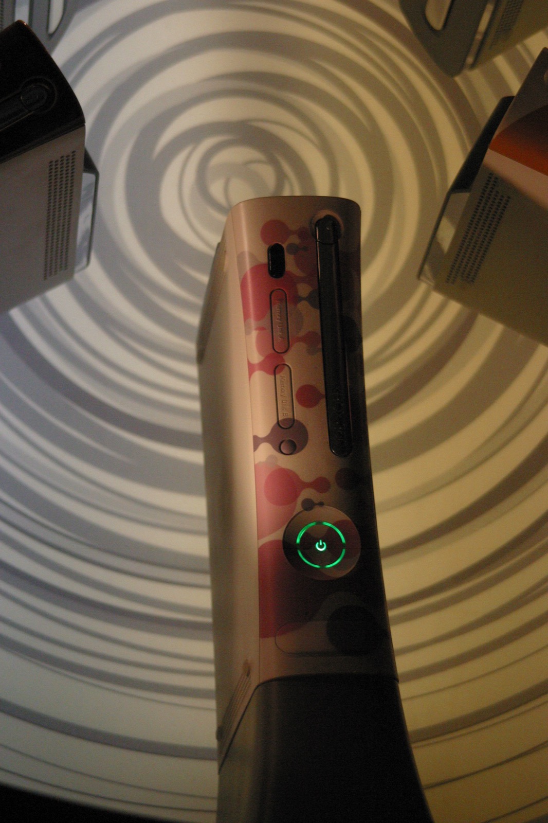 Close-up of a custom Xbox 360 faceplate with a pink and red artistic design.